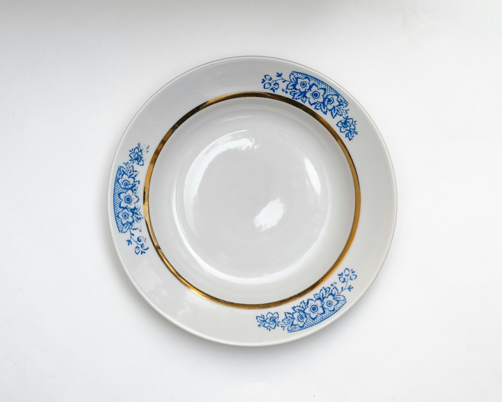 A white plate with blue flowers and gold trim